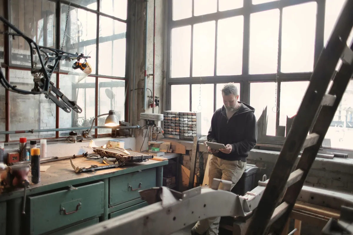 Tradesperson using a tablet beside a workshop window