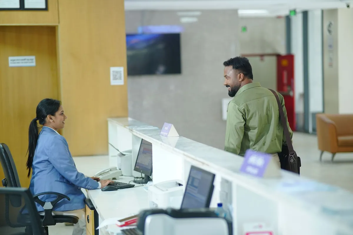 Guest and receptionist talking across a modern hotel front desk